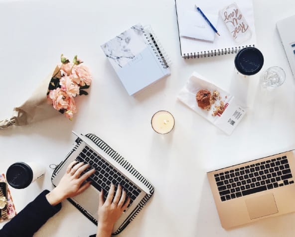 Business continuity planning workspace with laptops, notebooks, and coffee for SEC cybersecurity compliance.
