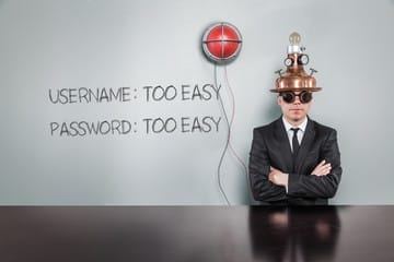Man in suit wearing a comical mind-control helmet beside a red target, with “USERNAME: TOO EASY” and “PASSWORD: TOO EASY” written on a whiteboard—highlighting the risks of weak default credentials in network security.