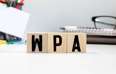 Wooden blocks on a desk spelling "WPA," symbolizing the importance of using WPA encryption protocols to strengthen Wi-Fi network security.