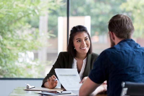 Two professionals discussing documents across a table, representing consultation or debriefing after a website breach response.