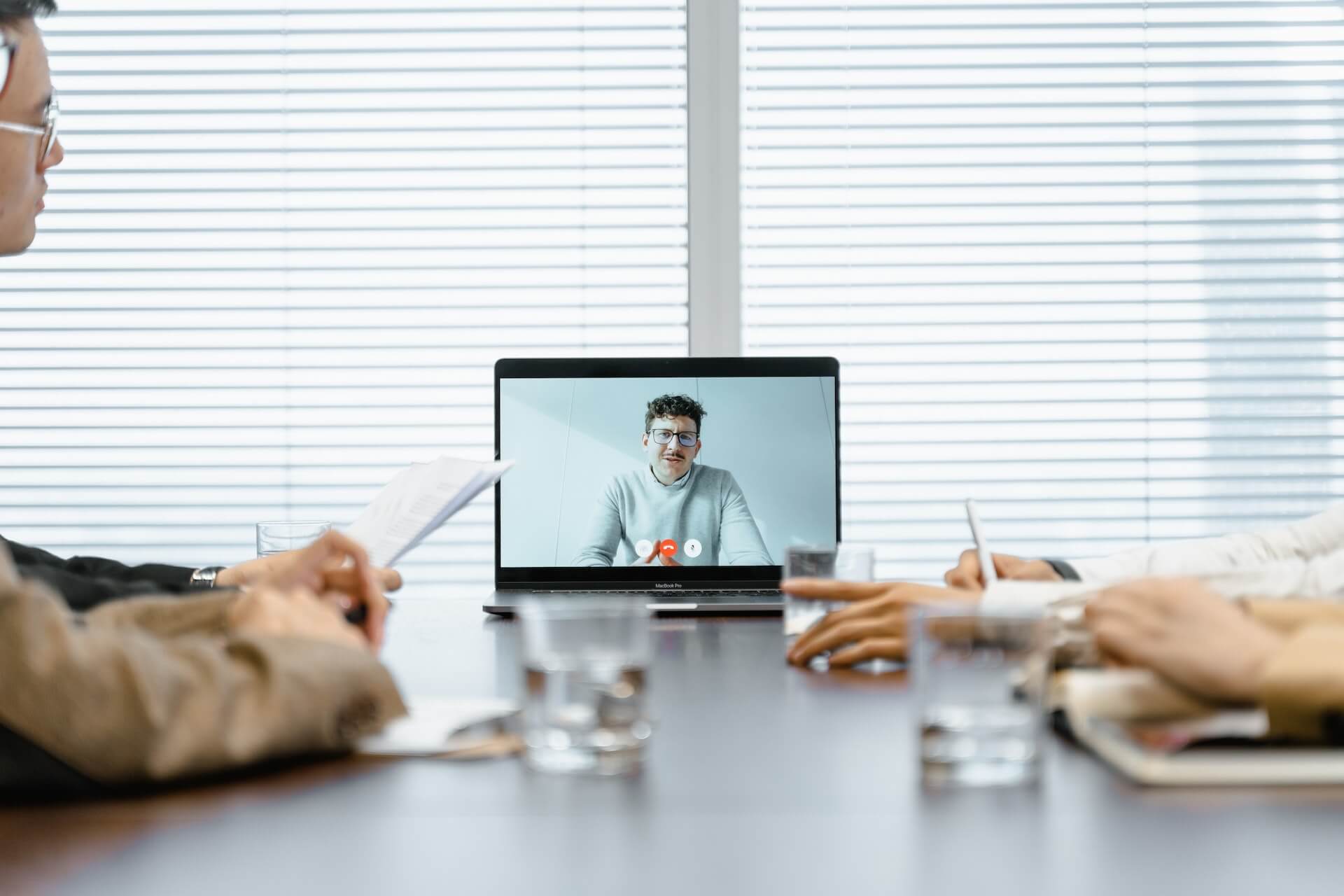 In-person team meeting virtually collaborating with a remote expert shown on a laptop screen, illustrating support and coordination in responding to a hacked website incident.